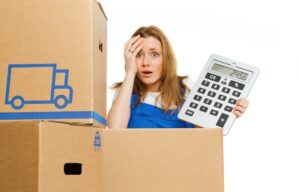 Woman holding a calculator beside moving boxes