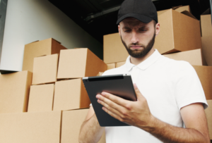 Man checking a tablet beside stacked moving boxes